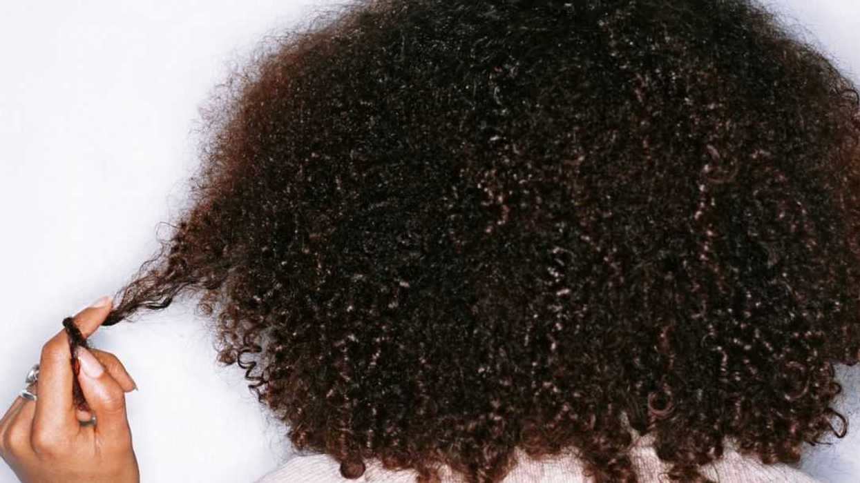 Young woman twisting hair around finger, rear view.