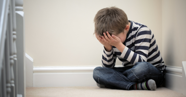 young boy sitting on the floor, crying