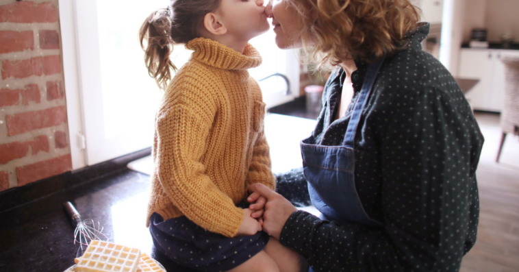 Young girl kissing her mom on the nose
