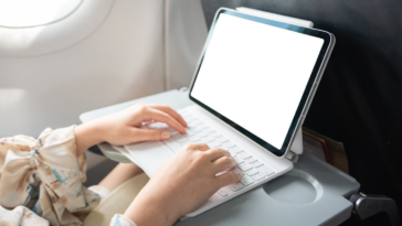Person typing on computer on airplane