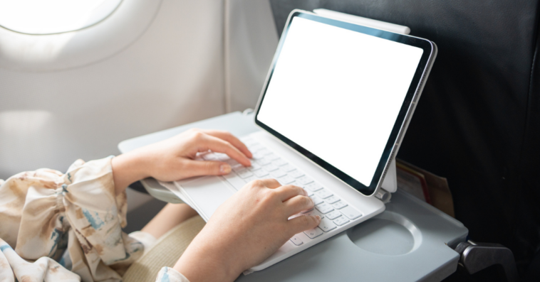 Person typing on computer on airplane