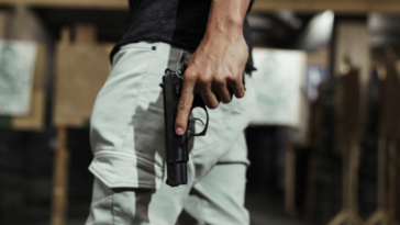 A man holding a gun, finger off the trigger