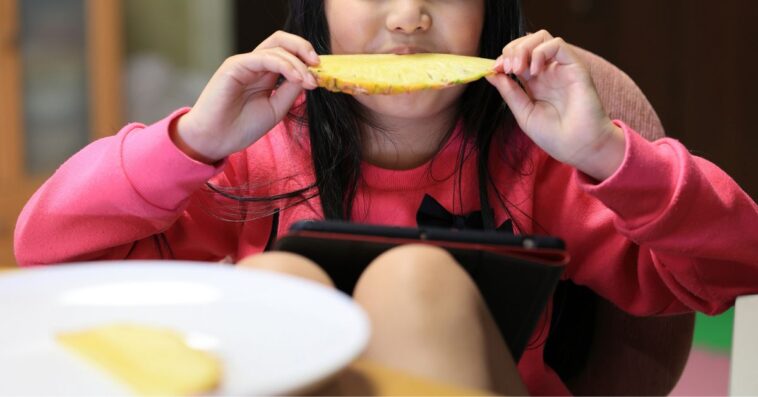 little girl enjoying a pineapple slice