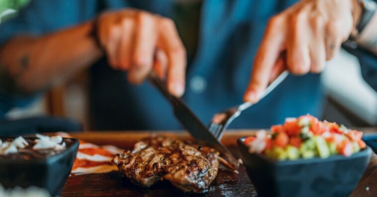 Hands of a man cutting into a steak