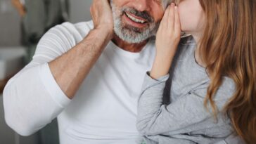 A daughter whispers in her dad's ear