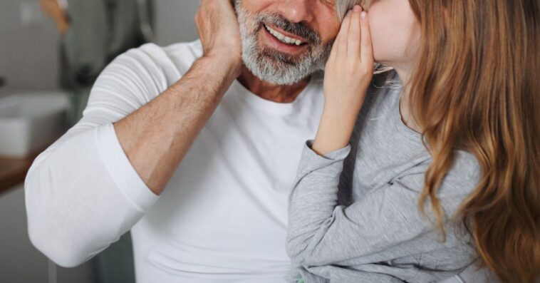 A daughter whispers in her dad's ear