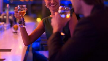 A man and woman drink and flirt in a dimly lit bar