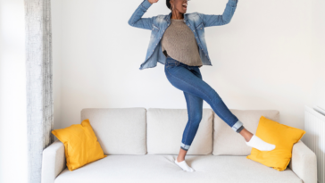 Woman in skinny jeans dancing on couch