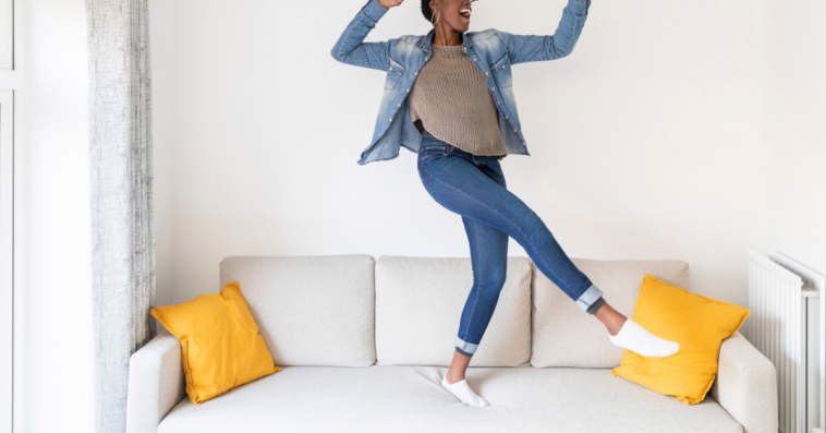 Woman in skinny jeans dancing on couch