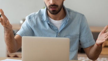 man looking at laptop with shocked expression
