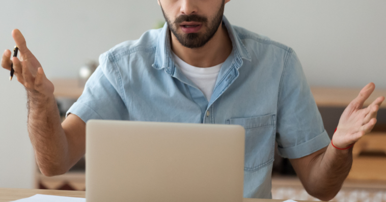 man looking at laptop with shocked expression