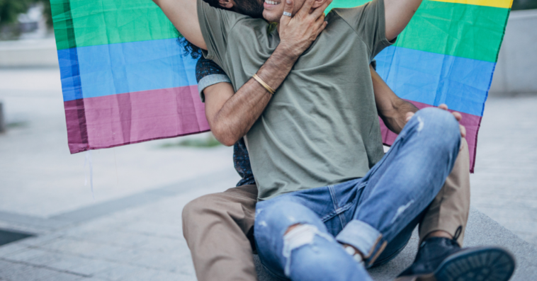 gay male couple under a pride flag