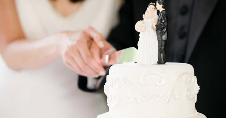 Couple cutting wedding cake.