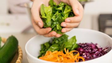 woman's hands adding chopped vegetables to bowl