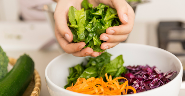 woman's hands adding chopped vegetables to bowl