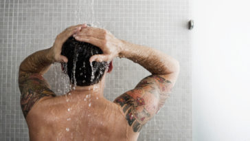 A man showers, back to the camera