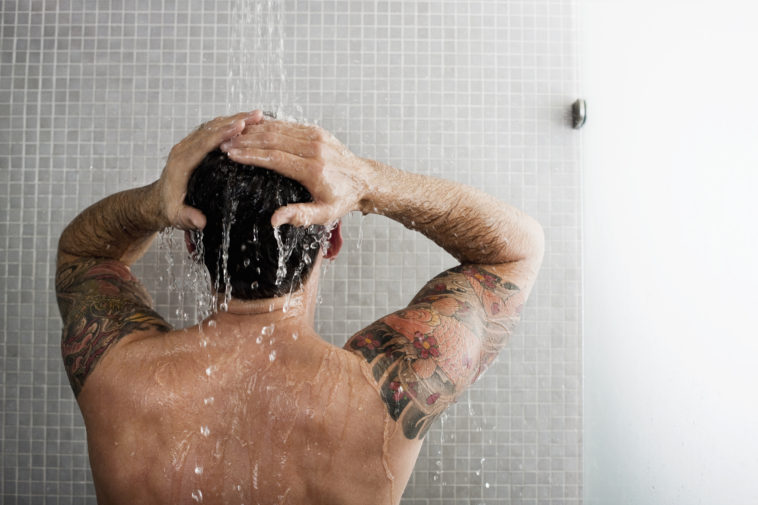 A man showers, back to the camera