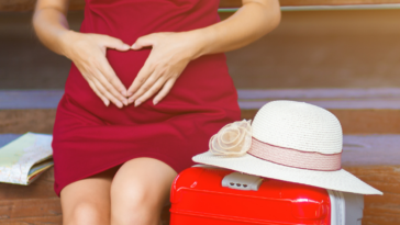 Pregnant woman sitting on bench with suitcase
