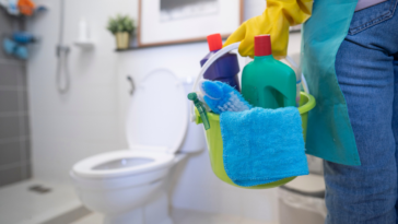 Woman approaching toilet with cleaning supplies