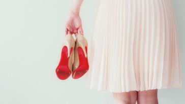 A woman holds a pair of red heels