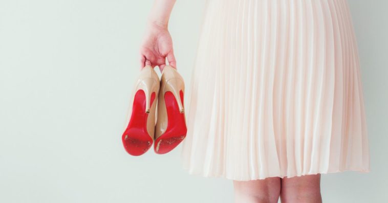 A woman holds a pair of red heels