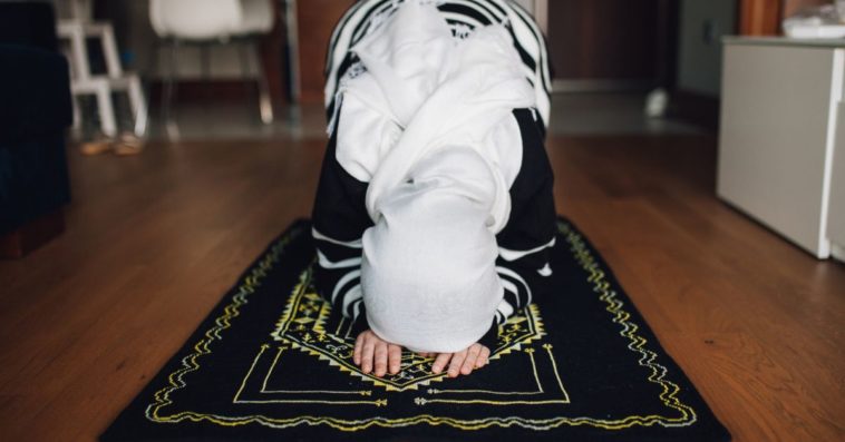 A muslim woman prays on a carpet