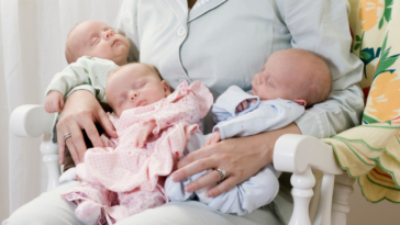 Mother with sleeping triplet newborn babies