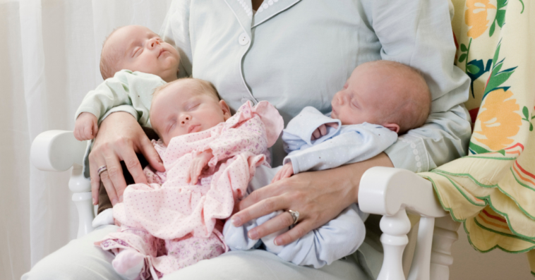Mother with sleeping triplet newborn babies
