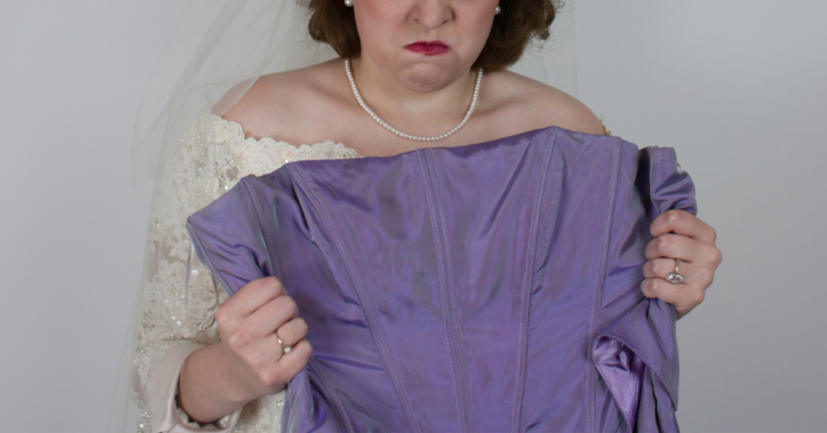 Angry bride holding up bridesmaid's dress