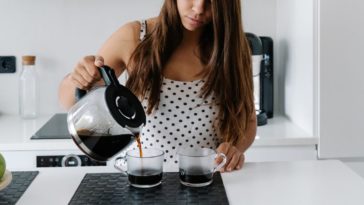 A woman pours two cups of coffee