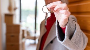 An older woman holds out a key