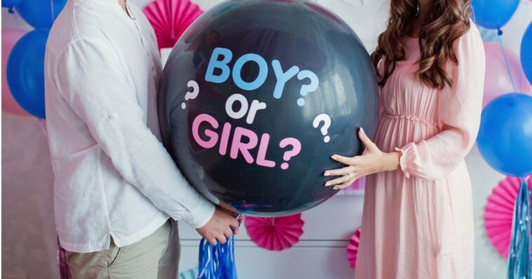A man and woman hold a black balloon asking "Boy or Girl?"