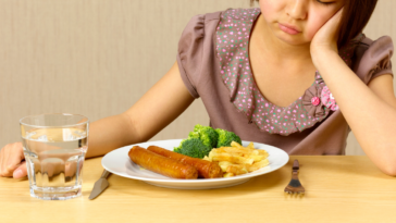 Girl scowling at plate of food