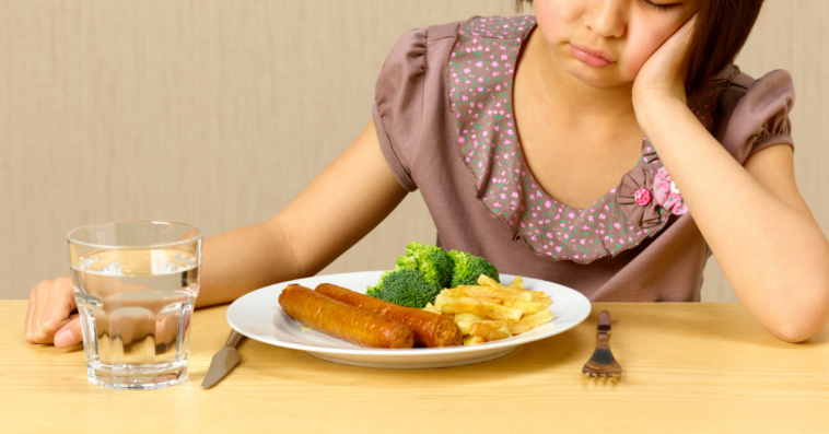 Girl scowling at plate of food