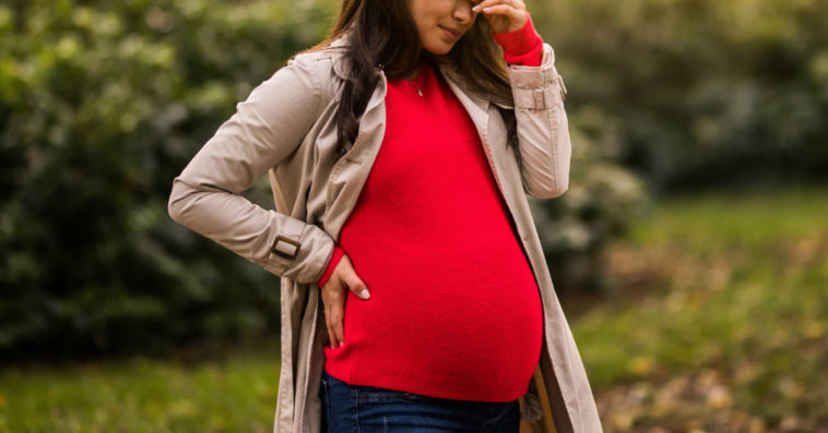 Distressed pregnant woman standing outside