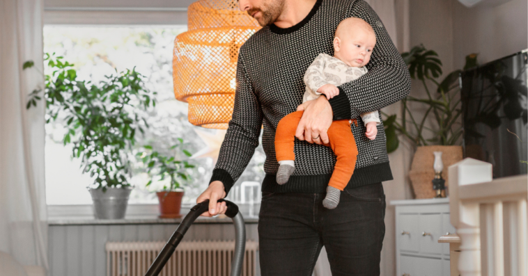 Man cleaning home while holding baby