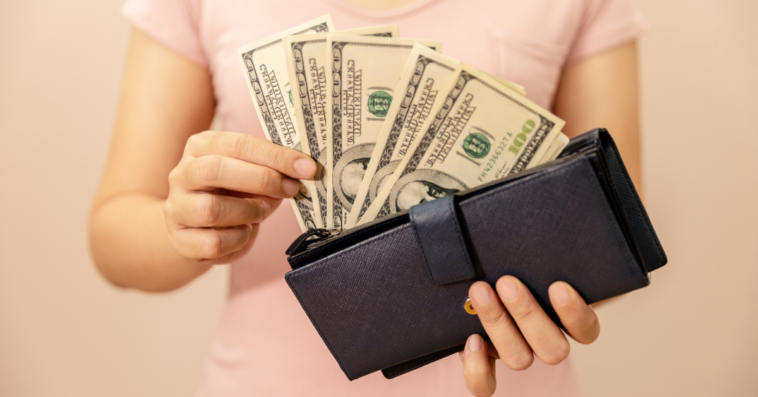Woman holding wallet full of cash