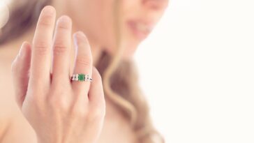 A woman holds up an emerald ring
