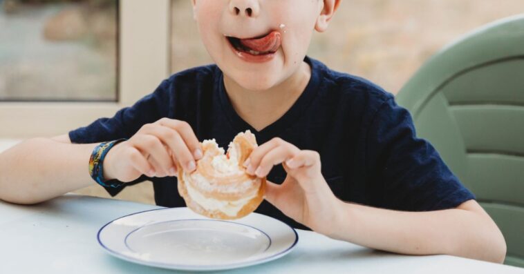A young boy licks his lips after eating