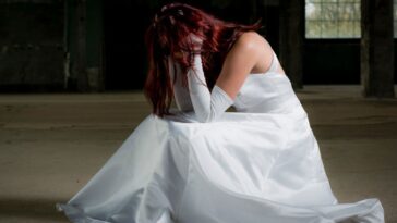 A bride kneels down with her head in her hands