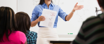 Female teacher presenting at the front of classroom