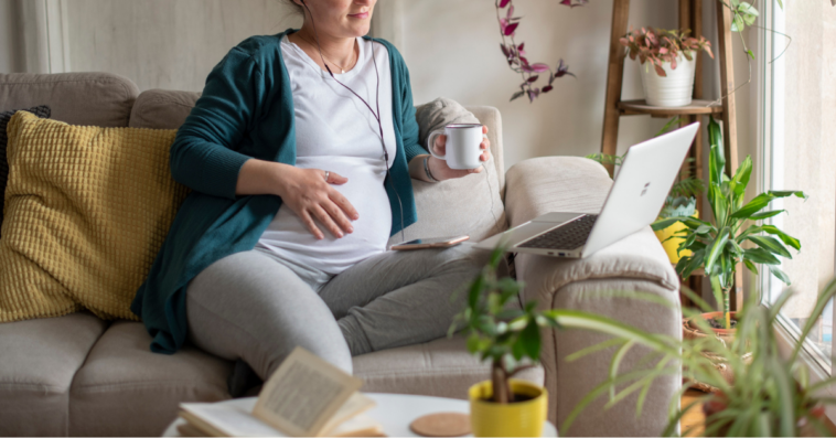 Pregnant woman working from home on a couch with laptop