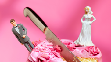 a wedding cake with a knife between the bride and groom cake toppers