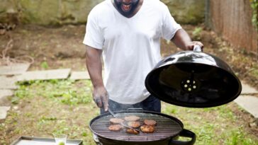 A man grill burgers in the backyard