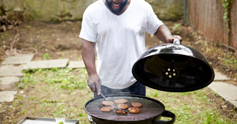 A man grill burgers in the backyard
