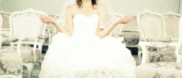 A bride sits with her arms out weighing options