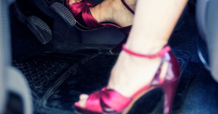 A woman's feet in fancy heels pushing car pedals