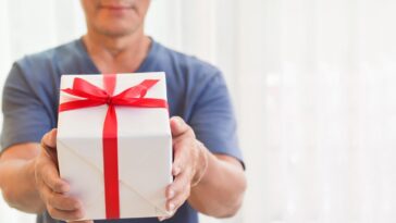 A man presents a gift, white box, red ribbon