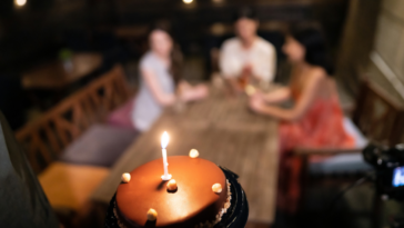 Waiter bringing birthday cake to table of 3 women