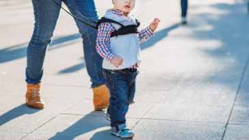 Adult walking with child, using a retractable leash
